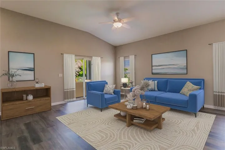 Living area with dark wood-style floors, vaulted ceiling, and ceiling fan