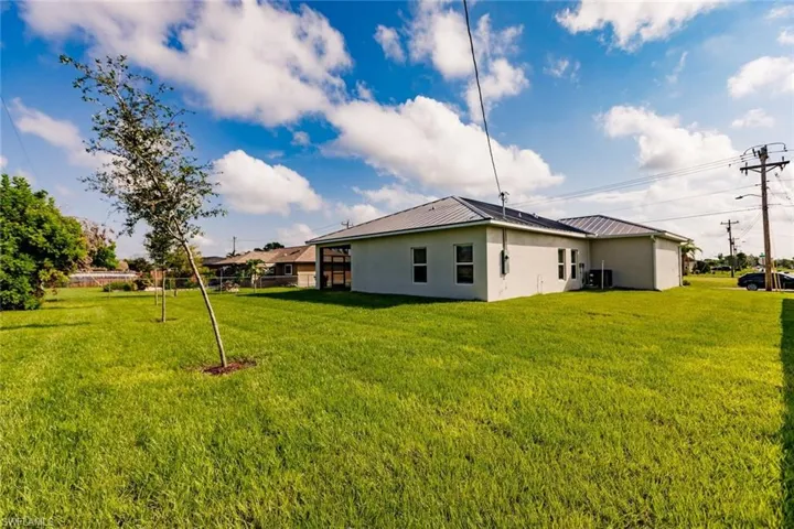 Back of property featuring stucco siding, a lawn, and a metal roof