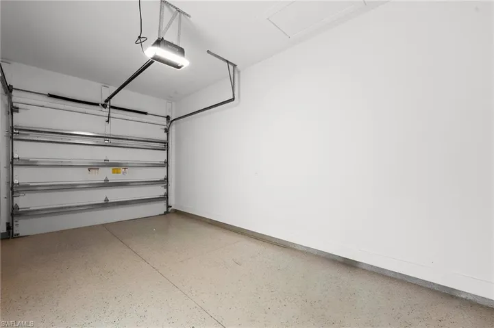 Spacious garage featuring an automatic overhead door, overhead lighting, and concrete flooring