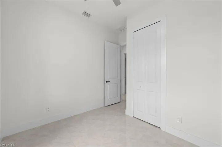 Neutral-toned room featuring light-colored tile flooring, white walls, and a bi-fold closet door