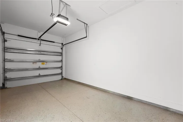 Garage interior featuring an automatic overhead door, epoxy floor coating, and a ceiling-mounted light fixture