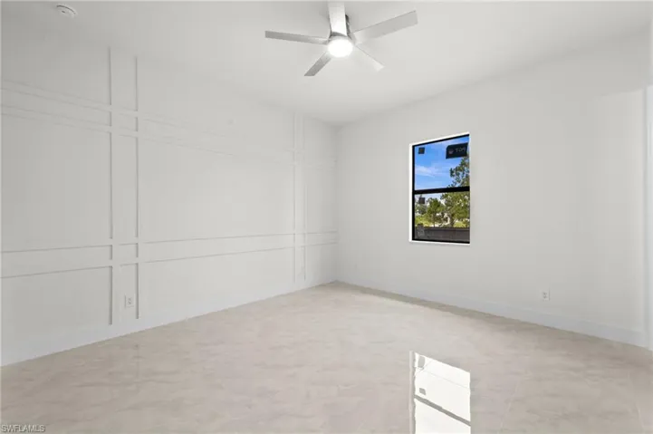 Spacious room featuring light-toned tile flooring, a contemporary ceiling fan, and decorative wall molding