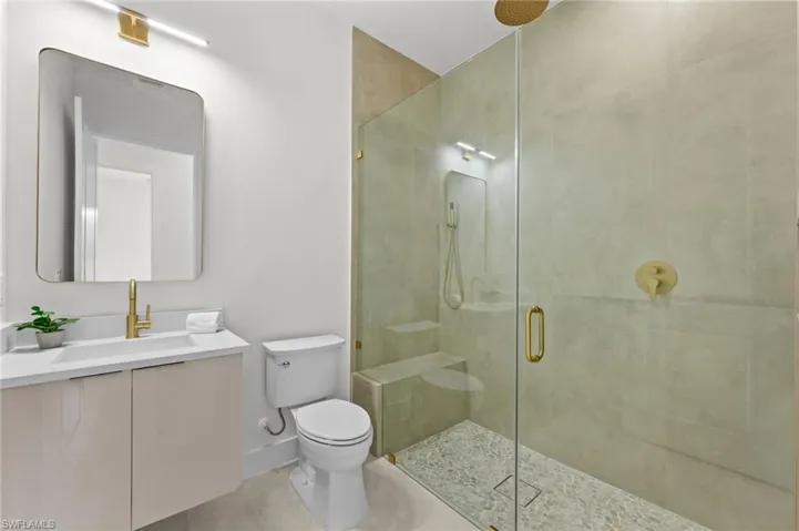 Modern bathroom featuring a frameless glass shower enclosure with a rain shower head and pebble-tiled floor