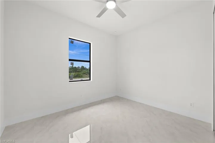Bright interior room featuring a large window with black trim, tile flooring, recessed lighting, and a ceiling fan