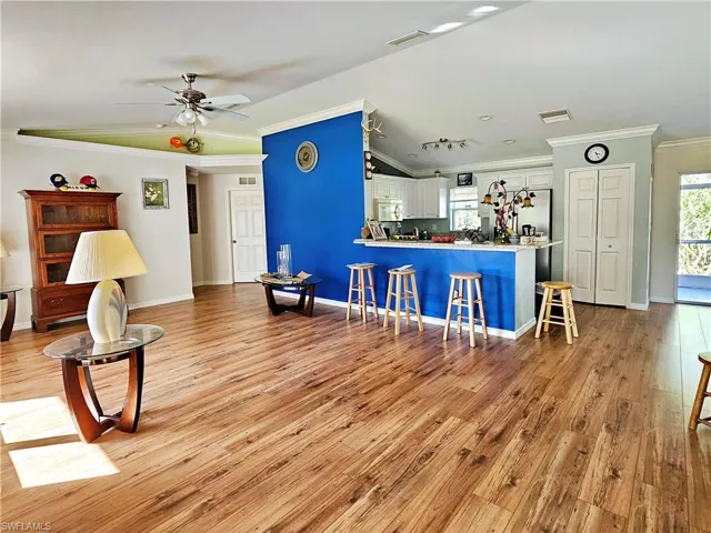 Living room with ceiling fan, ornamental molding, and light hardwood / wood-style flooring