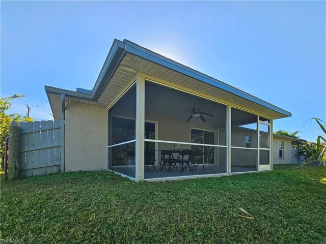 Back of property featuring a sunroom, ceiling fan, and a yard
