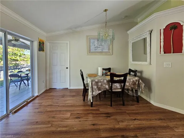 Dining area featuring lofted ceiling, ornamental molding, dark wood-type flooring, and ceiling fan with notable chandelier