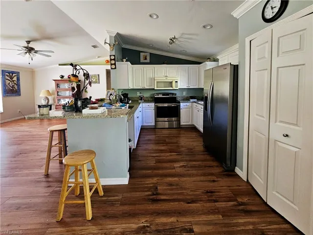 Kitchen featuring white cabinets, a kitchen breakfast bar, kitchen peninsula, and appliances with stainless steel finishes