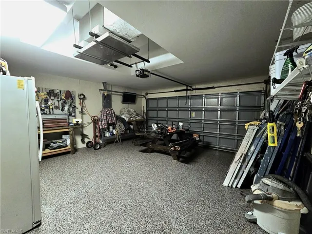 Garage featuring white refrigerator and a garage door opener