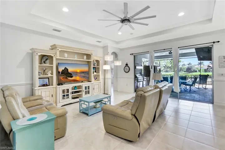 Living room featuring visible vents, arched walkways, a raised ceiling, and a ceiling fan