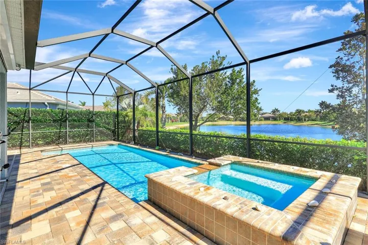 View of swimming pool featuring a patio area, a lanai, a water view, and a pool with connected hot tub