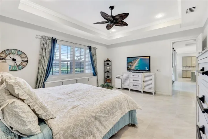 Bedroom with ornamental molding, a tray ceiling, and visible vents