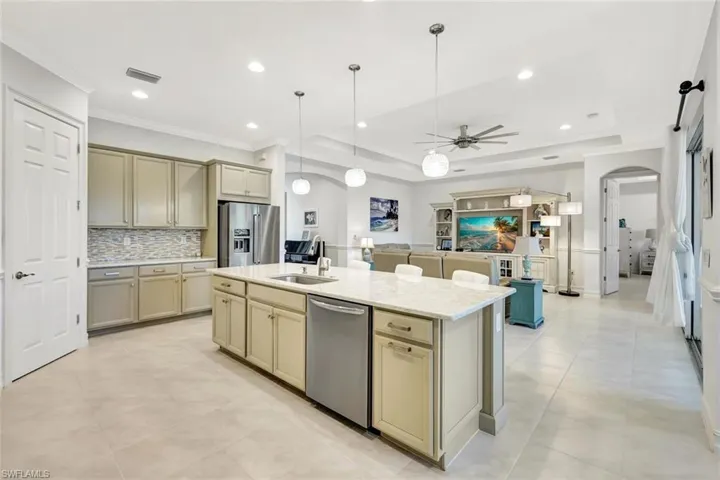 Kitchen featuring tasteful backsplash, arched walkways, cream cabinets, a tray ceiling, and stainless steel appliances