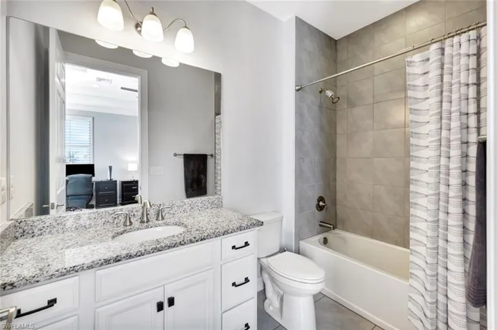 Ensuite bathroom with toilet, ensuite bath, tile patterned flooring, shower / bath combo with shower curtain, and vanity