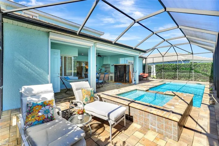 Outdoor pool featuring glass enclosure, a patio, and an in ground hot tub