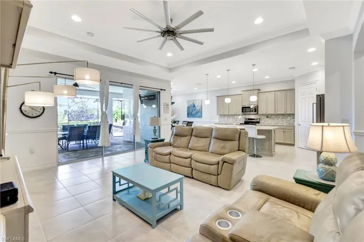 Living area with recessed lighting, a tray ceiling, ornamental molding, and light tile patterned flooring