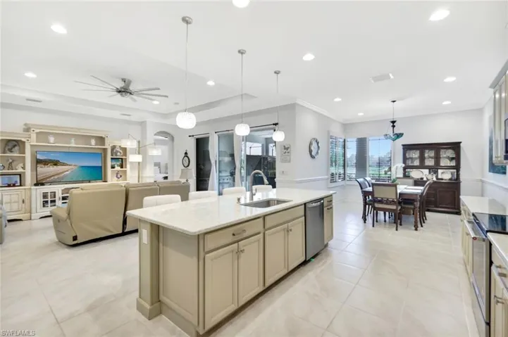 Kitchen with arched walkways, an island with sink, stainless steel appliances, a sink, and light tile patterned flooring