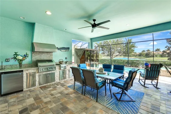 View of patio / terrace with ceiling fan, an outdoor kitchen, a lanai, a sink, and a grill