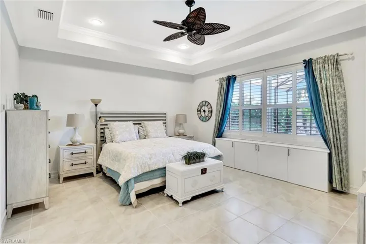 Bedroom featuring light tile patterned floors, visible vents, a ceiling fan, ornamental molding, and a raised ceiling