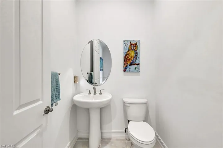 Half bath featuring baseboards, toilet, and tile patterned floors