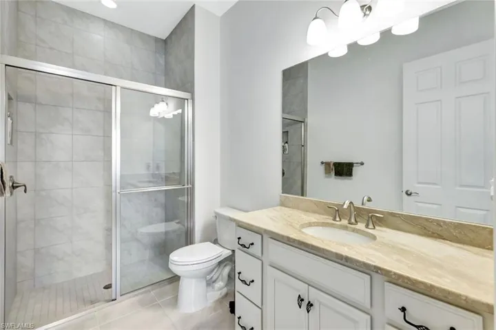 Full bath with vanity, tile patterned flooring, toilet, and a shower stall