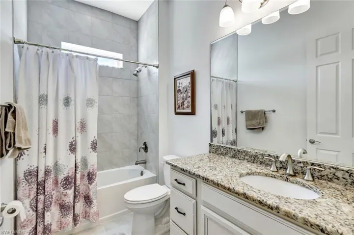Bathroom featuring shower / bath combo, vanity, toilet, and tile patterned floors