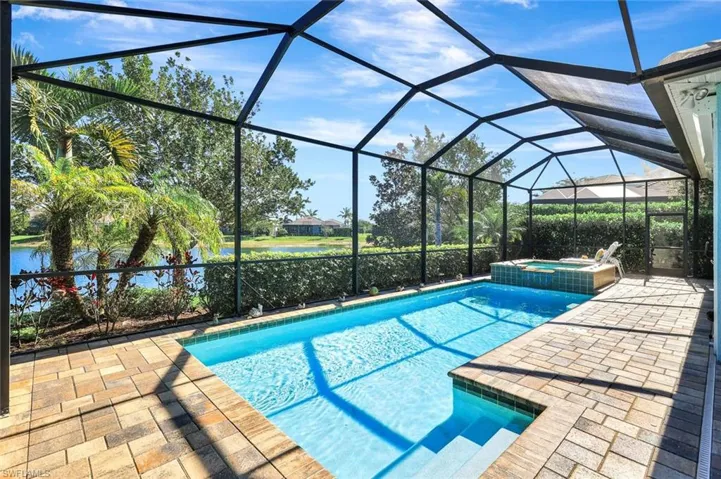 View of pool with a lanai, a pool with connected hot tub, and a patio