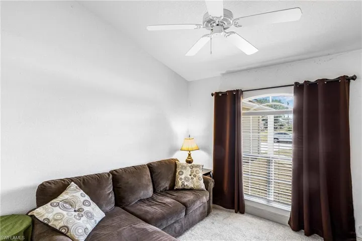 Living area with lofted ceiling, a ceiling fan, and carpet floors
