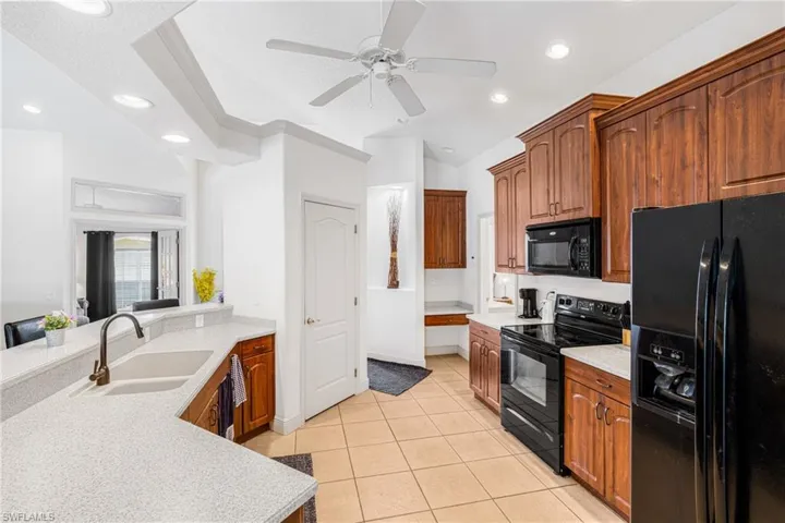 Kitchen with black appliances, light tile patterned flooring, a sink, and recessed lighting