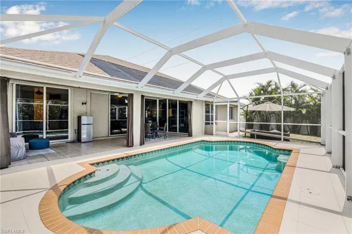 Outdoor pool with a ceiling fan, glass enclosure, and a patio