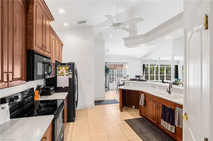 Kitchen featuring brown cabinetry, black appliances, a sink, and visible vents