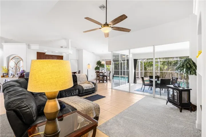 Living area featuring lofted ceiling, visible vents, a ceiling fan, and light tile patterned floors