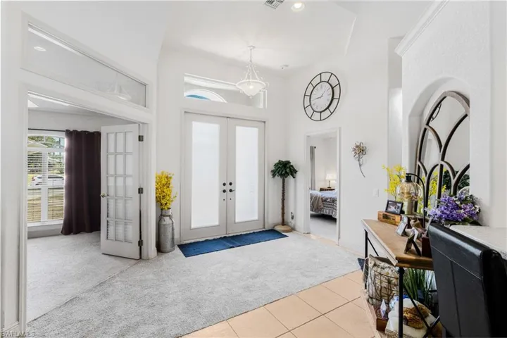 Carpeted entryway featuring tile patterned flooring, french doors, a towering ceiling, and visible vents