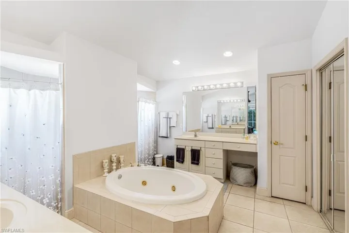 Full bath with curtained shower, tile patterned flooring, vanity, and a tub with jets