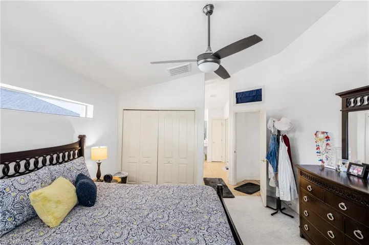 Primary Bedroom with a closet, vaulted ceiling, visible vents, and light carpet