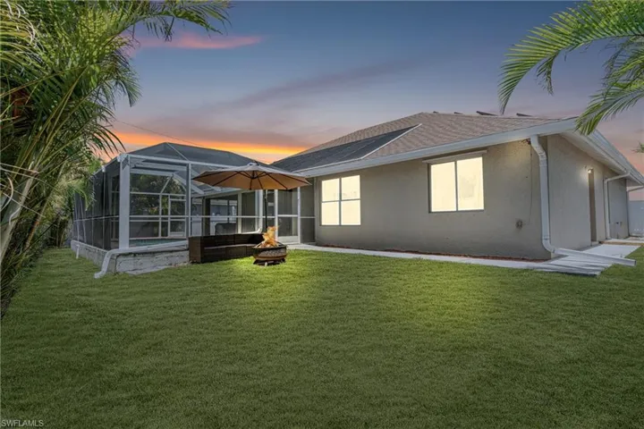Rear view of house featuring a fire pit, a yard, and stucco siding