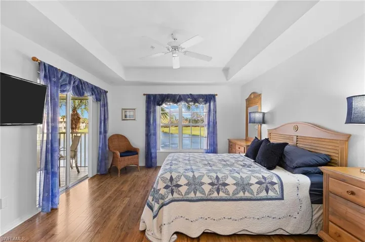 Bedroom featuring dark wood-type flooring, a raised ceiling, and ceiling fan