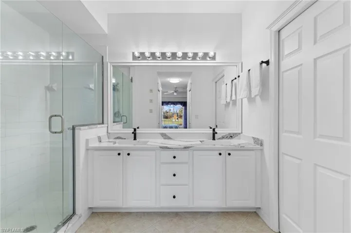 Bathroom featuring vanity, walk in shower, and tile patterned flooring