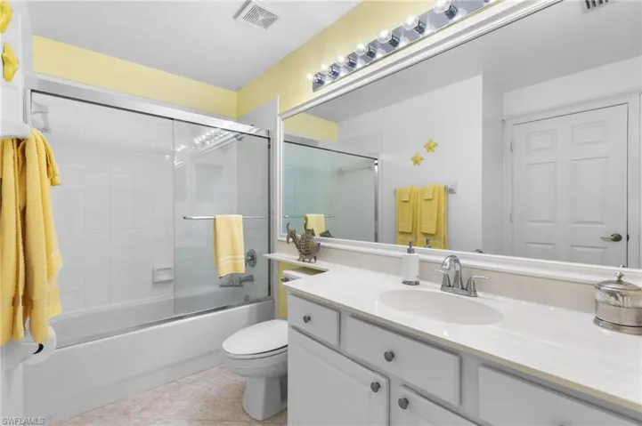 Full bathroom featuring vanity, bath / shower combo with glass door, toilet, and tile patterned floors