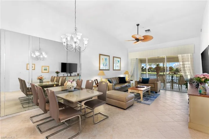 Dining area with high vaulted ceiling, ceiling fan with notable chandelier, and light tile patterned floors