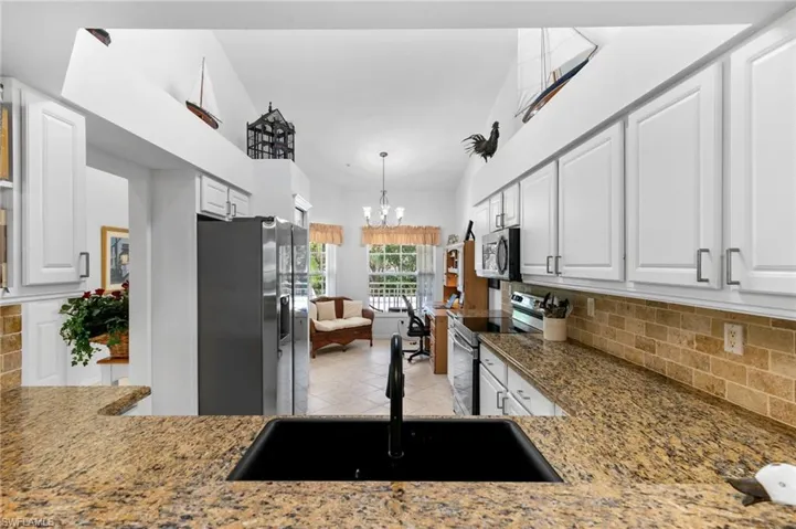 Kitchen with a notable chandelier, white cabinets, stainless steel appliances, and sink