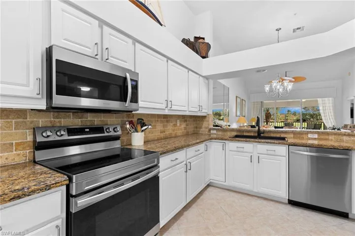 Kitchen with stainless steel appliances, sink, dark stone counters, and white cabinets