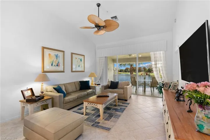 Living room featuring light tile patterned floors, high vaulted ceiling, and ceiling fan