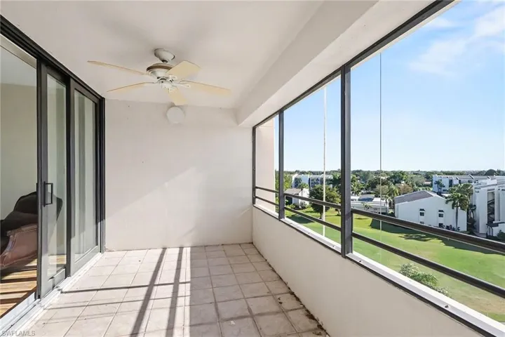 Unfurnished sunroom with ceiling fan and a balcony
