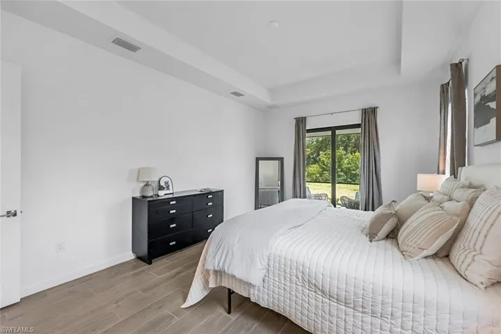 Bedroom featuring access to exterior, a tray ceiling, and hardwood / wood-style flooring