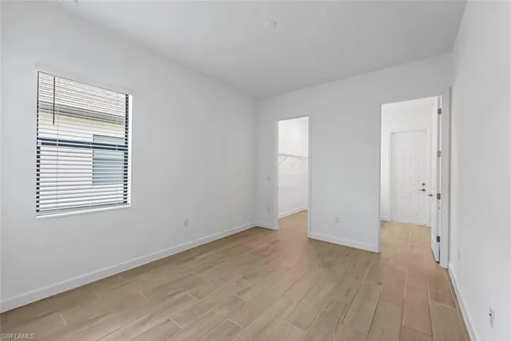 Unfurnished bedroom featuring a spacious closet, a closet, and light wood-type flooring
