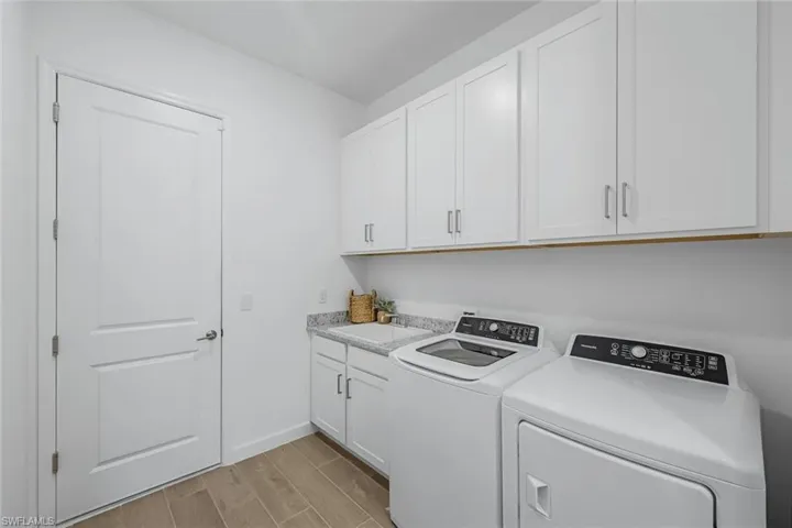 Laundry area with sink, light hardwood / wood-style flooring, independent washer and dryer, and cabinets