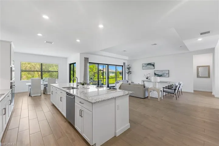 Kitchen with sink, dishwasher, a center island with sink, and white cabinetry