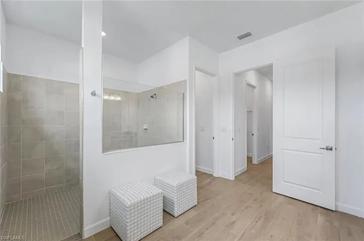 Bathroom featuring tiled shower and wood-type flooring
