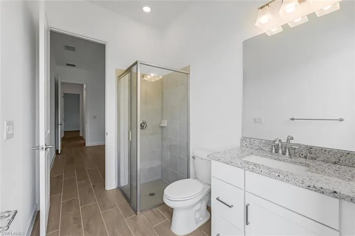 Bathroom with a shower with door, vanity, and toilet